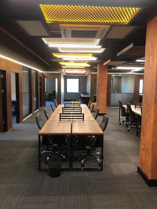 Modern coworking meeting room with linear tables for collaborative office workspace sessions.