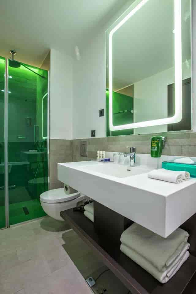 Modern hotel bathroom with illuminated vanity mirror for business travel and event accommodation.
