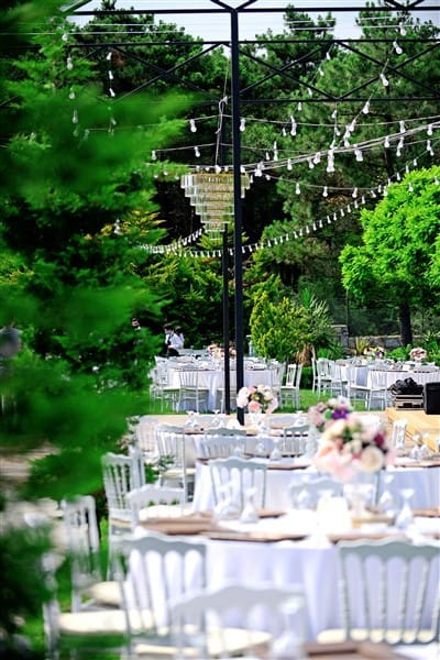 Upscale outdoor event at Park Lotus garden featuring elegant white tablescapes and bistro lighting.