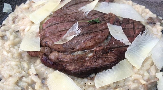 Plated steak with mushroom risotto at a MYK Gastro Arena cooking school banquet dinner service.