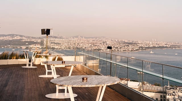 High-end rooftop bar with marble tables and cityscape view for cocktail receptions and networking.