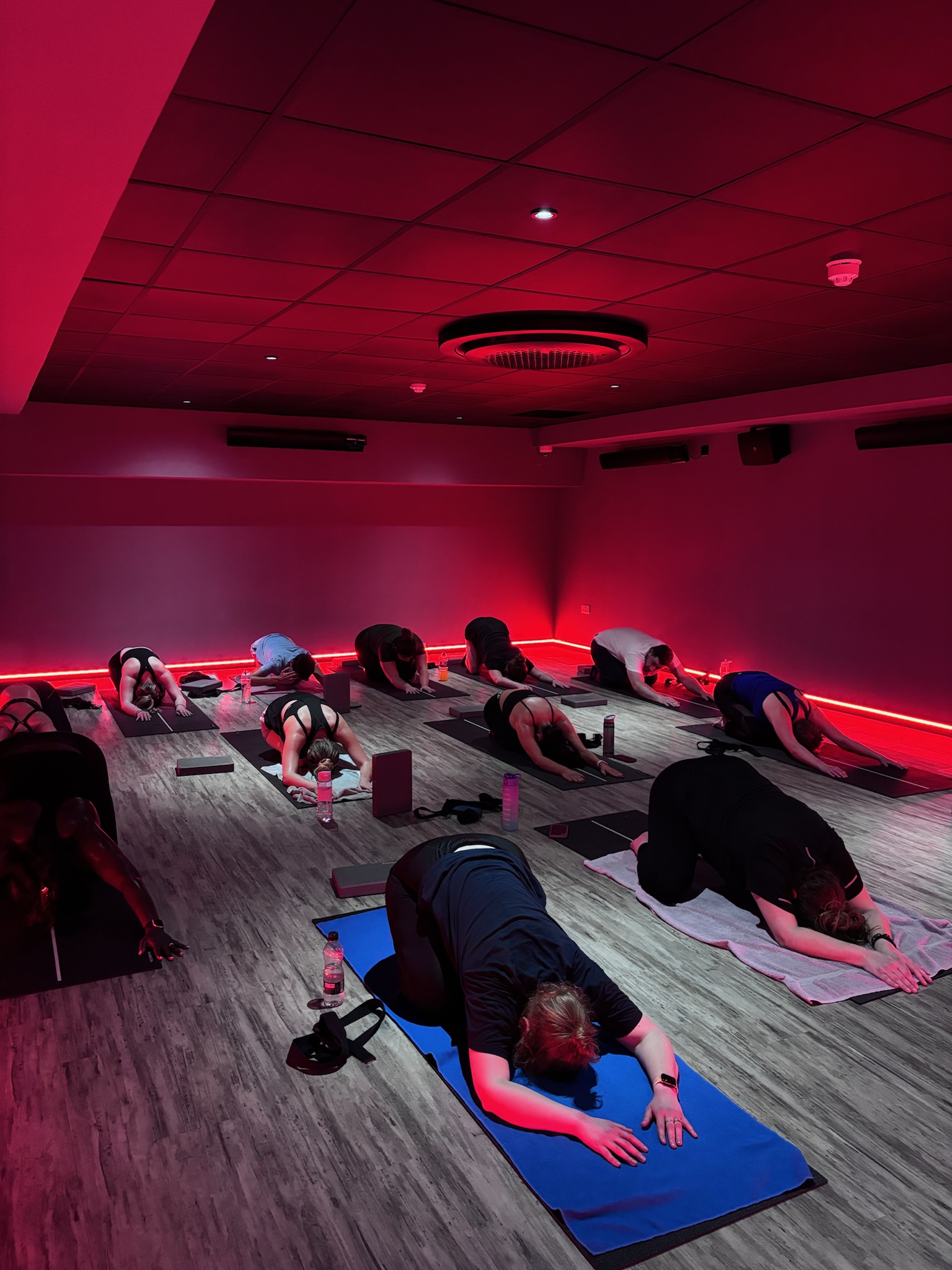 Corporate wellness yoga session in a fitness studio with immersive lighting.