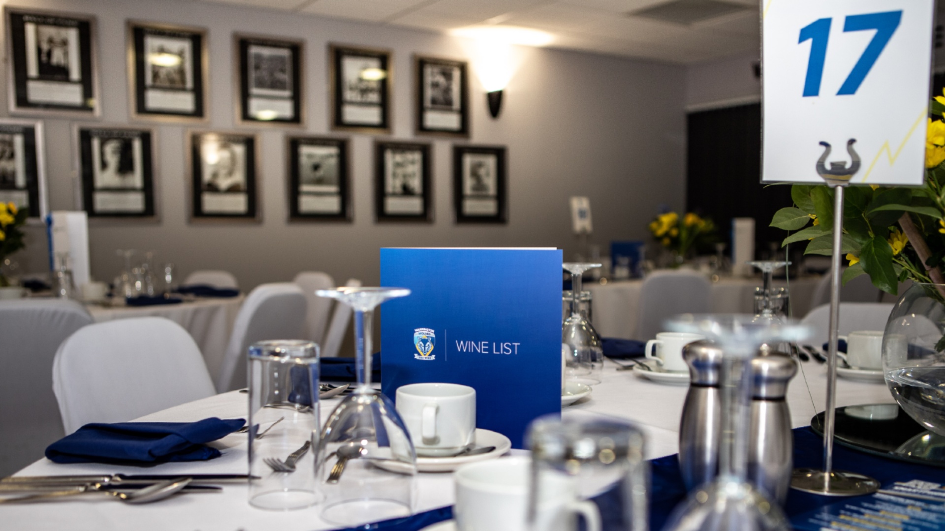 Hall of Fame Lounge gala dinner setup with formal table linens at Halliwell Jones Stadium. - Banner