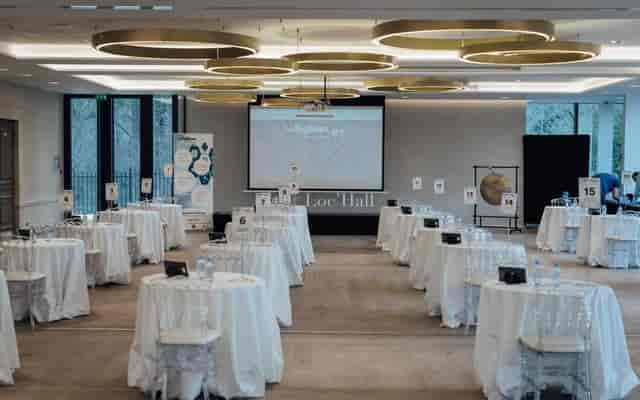 Modern ballroom event space with round tables for networking and corporate conference setup.