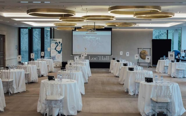 Modern ballroom event space with round tables for networking and corporate conference setup.