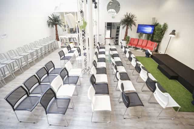 Modern HUBLOFT conference room with artificial turf stage for corporate workshops and panels.