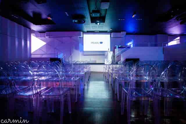 Modern Elyseum banquet hall with tiered seating and ghost chairs for corporate event presentations.