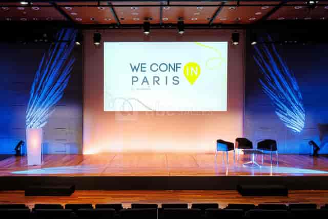 Modern auditorium stage set for corporate plenary session and fireside chat branding.