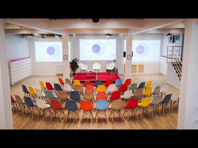 Modern Espace Batignolles conference venue with colorful chairs for panel discussion event.