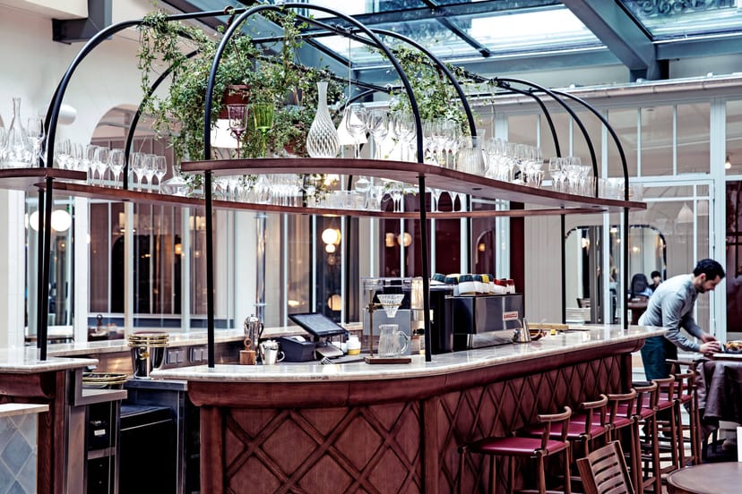 Modern conservatory event space at Grand Pigalle with central bar for corporate networking events.