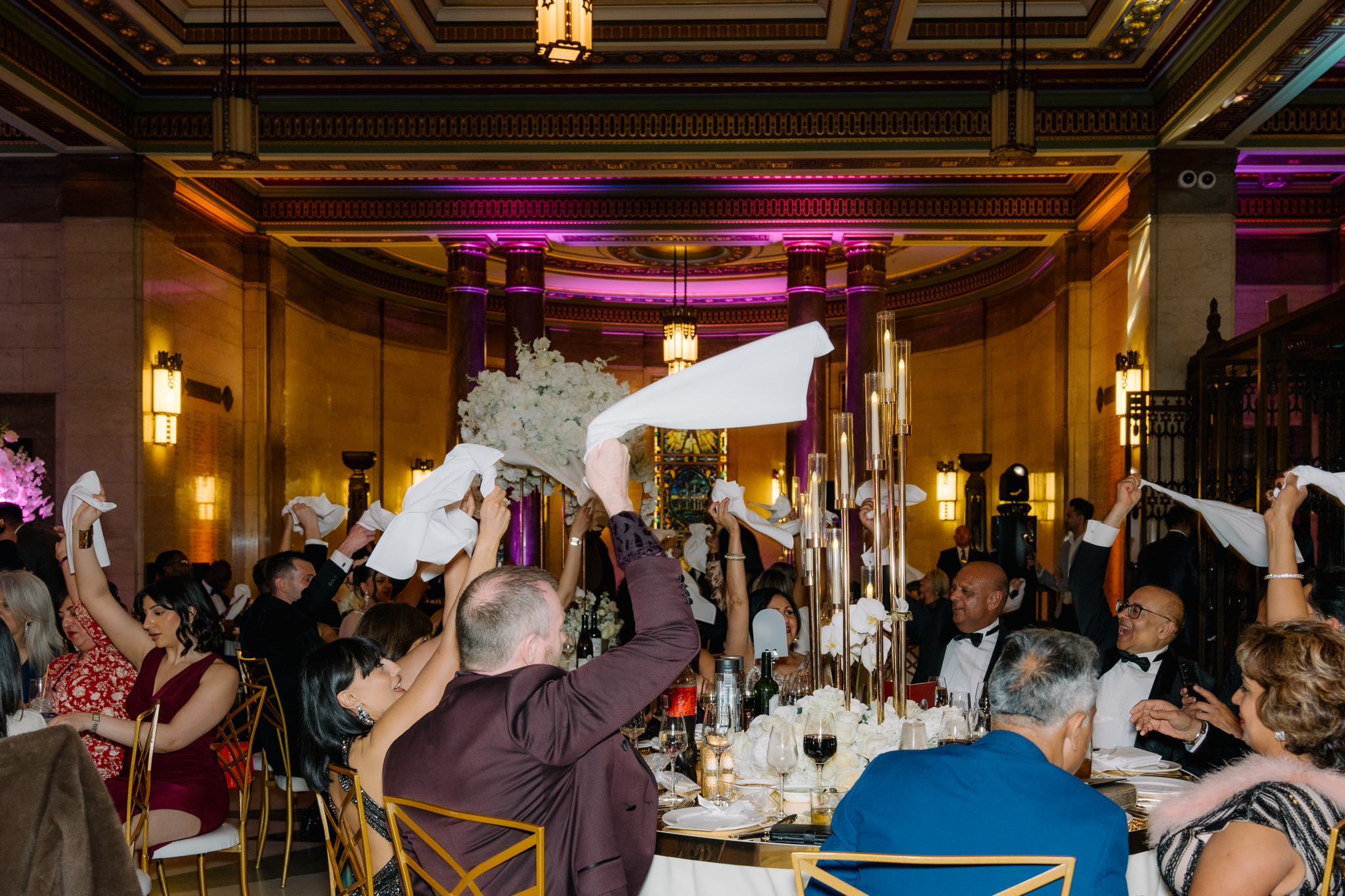Alt text: Vibrant gala in The Long Room, guests cheer with napkins raised, elegant decor. - Banner