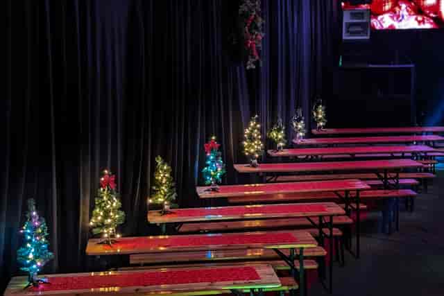 Festive holiday party setup with communal tables and Christmas trees at UnderTheArches event venue.