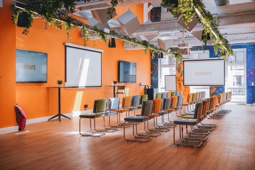Vibrant theater-style meeting room with orange walls for creative workshops and presentations.