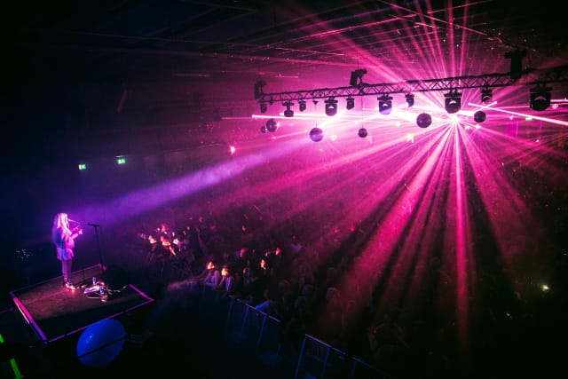 Solo performer on a high-impact, dramatically lit stage for entertainment or keynote event.