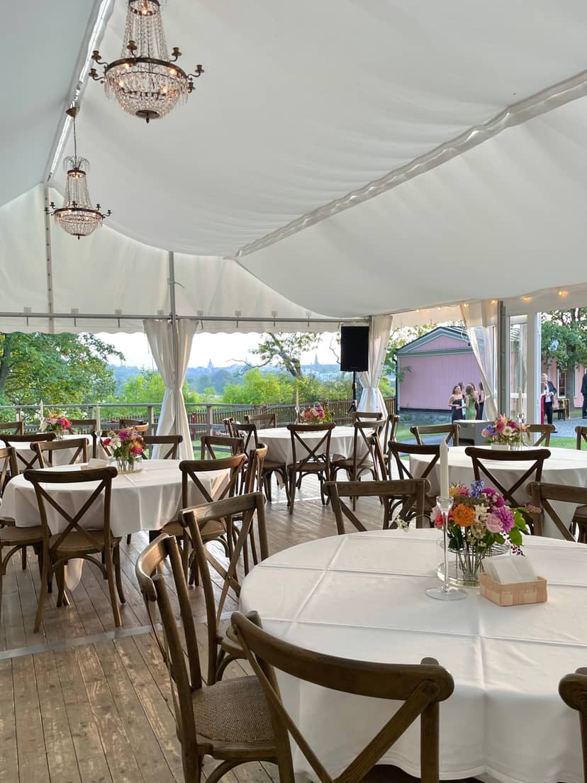 Clear-span marquee garden event setup with elegant cross-back chairs at Kungliga Borgen.