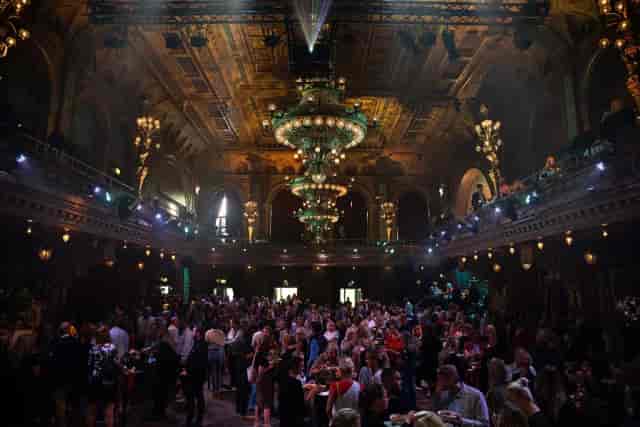 Ballroom reception with grand chandelier for sophisticated corporate networking event.