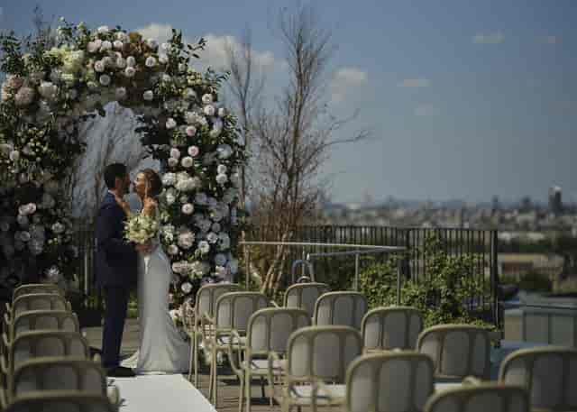 Outdoor wedding at JOIA Rooftop with floral arch and city skyline backdrop.