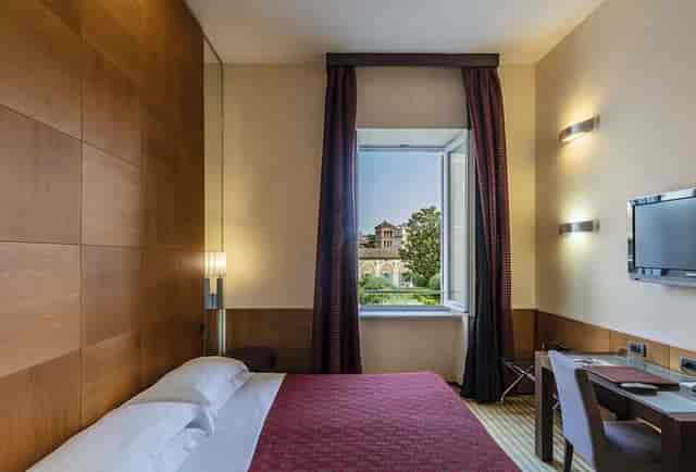 Kolbe Hotel Rome suite with dedicated workspace for business travel and courtyard view.