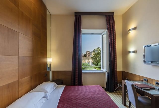 Kolbe Hotel Rome suite with dedicated workspace for business travel and courtyard view.