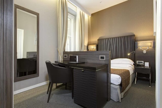 Hotel Artemide single suite with dedicated workspace for business conference travel.