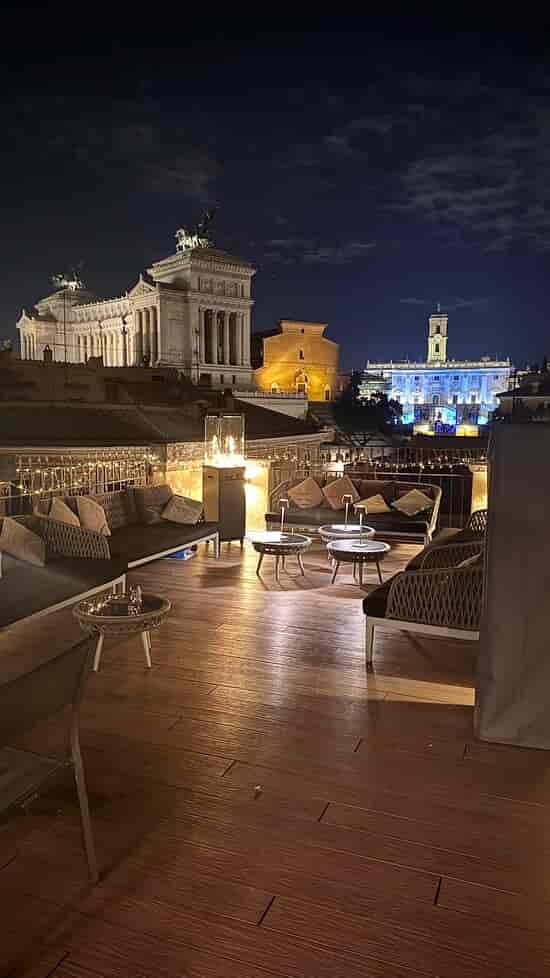 VIP cocktail reception at Rome rooftop bar with ambient lighting and plush lounge seating.