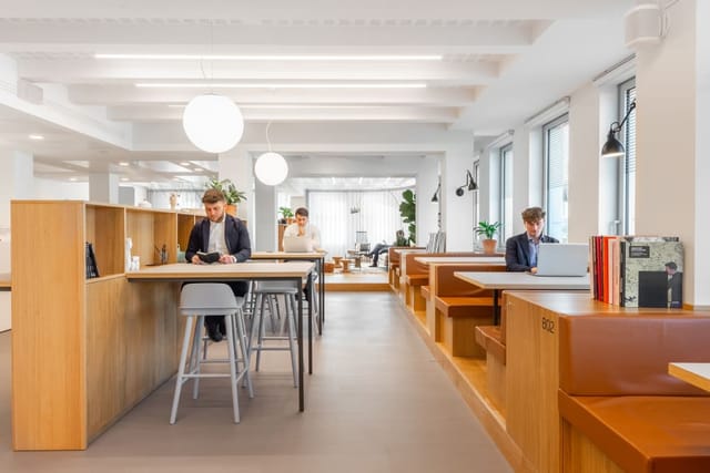 Co-working breakout space with high-top tables and booths for corporate meetings and team events.