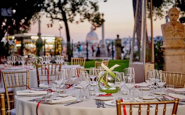 Outdoor gala at Casina Valadier, Sala Romana with sunset tablescape and gold Chiavari chairs.