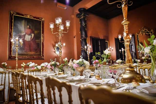 Gold Chiavari chairs and candelabras in Villa Giovanelli banquet hall for luxury wedding event.