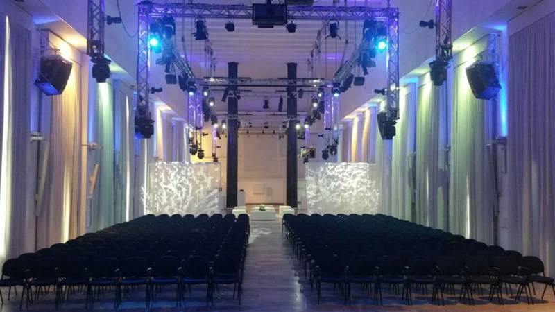 Spazio Novecento industrial venue with theater seating for corporate keynote and AV production.
