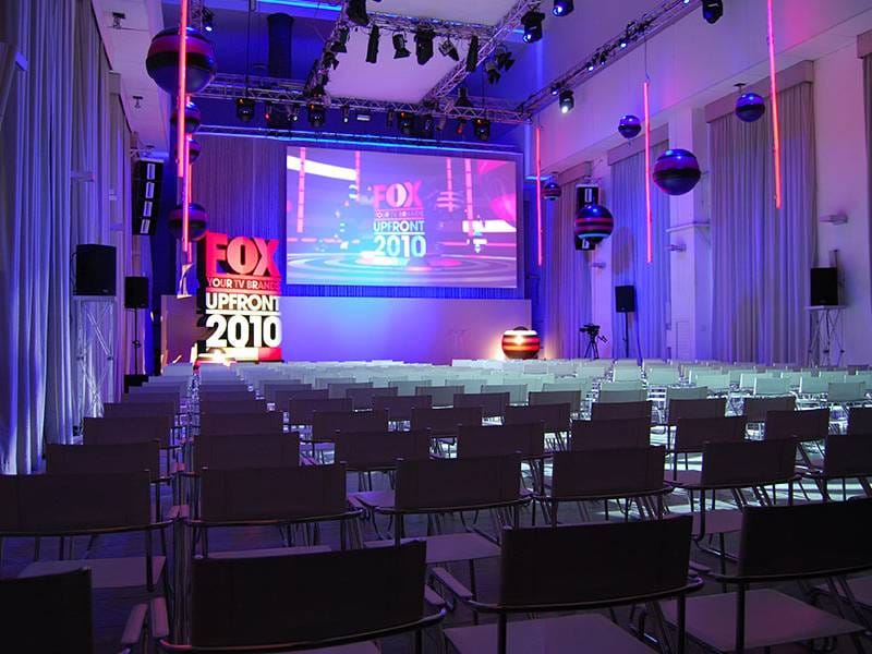 Corporate presentation in Spazio Novecento theater with projection screen and ambient lighting.