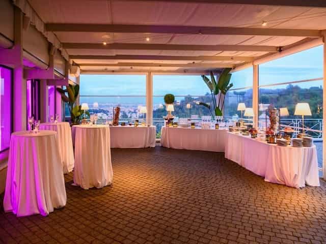 Cocktail reception at Villa Vittoria with high-top tables, purple lighting, and panoramic views.