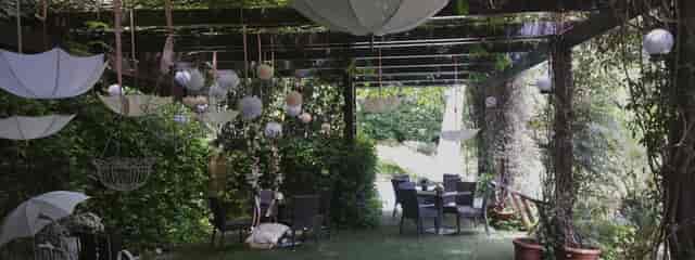 Outdoor party venue with suspended umbrellas and pom-poms for garden events and wedding planning.