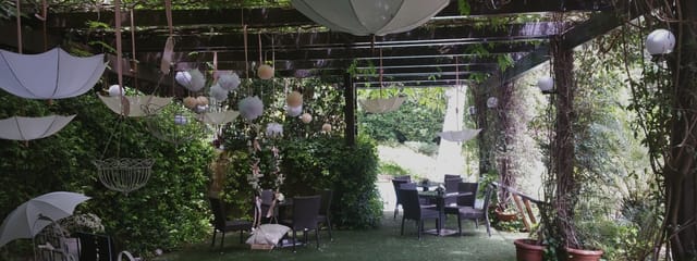 Outdoor party venue with suspended umbrellas and pom-poms for garden events and wedding planning.
