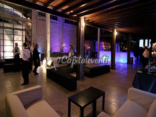 Industrial-chic banquet hall at Officine Farneto with atmospheric lighting for corporate networking.