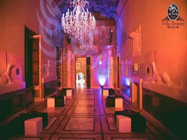 Upscale cocktail reception in Villa Brasini's historic Hall of Carriages with architectural lighting.