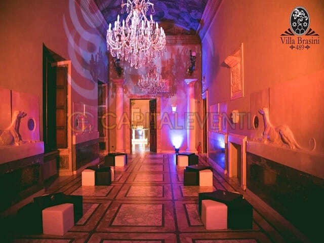 Upscale cocktail reception in Villa Brasini's historic Hall of Carriages with architectural lighting.