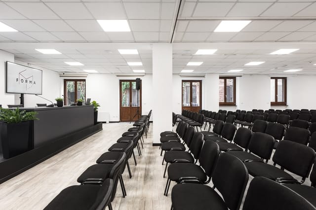 Minimalist Sala Q meeting room with AV stage for corporate training and seminars.