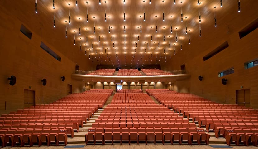Tiered auditorium with wood paneling for keynote sessions and awards galas at Centro Congressi.