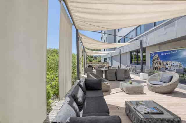 Covered terrace at H10 Roma Città with lounge furniture for corporate events and networking.