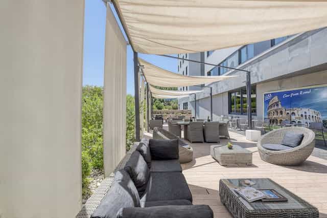 Covered terrace at H10 Roma Città with lounge furniture for corporate events and networking.