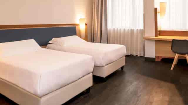 Modern twin hotel room with workspace at Mercure Eur Roma West for business conferences.