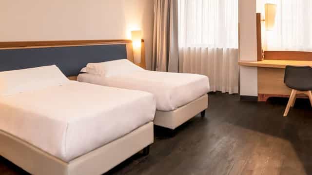 Modern twin hotel room with workspace at Mercure Eur Roma West for business conferences.