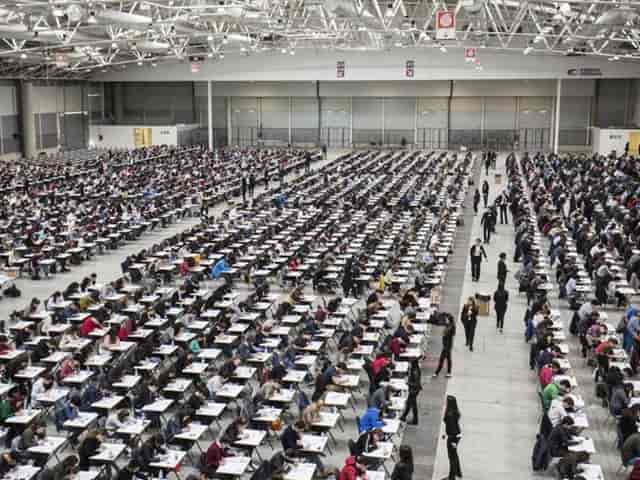 Classroom-style setup at Fiera Roma exhibition hall for large-scale examination event.
