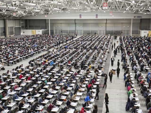 Classroom-style setup at Fiera Roma exhibition hall for large-scale examination event.