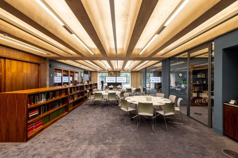 Modern library meeting room with circular tables, ideal for events and collaboration. - Banner