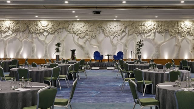 Crowne Plaza ballroom with stage and architectural wall for corporate events and panel discussions.