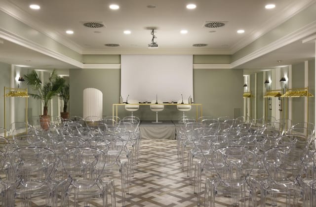 Sala Cassiopea theatre setup with ghost chairs for high-end panel discussion event space.