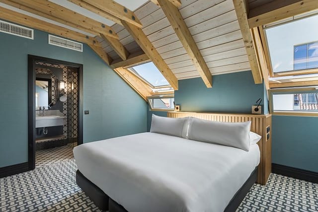 Alba Room Mate boutique suite with exposed wooden beams, ideal for VIP event room blocks.