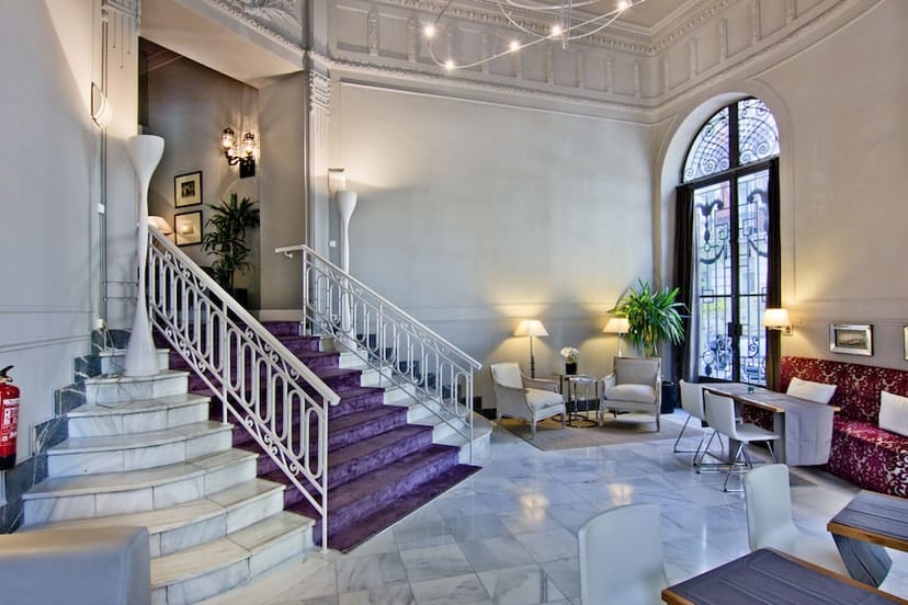 Boutique hotel lobby with grand staircase for intimate corporate event registration and networking.