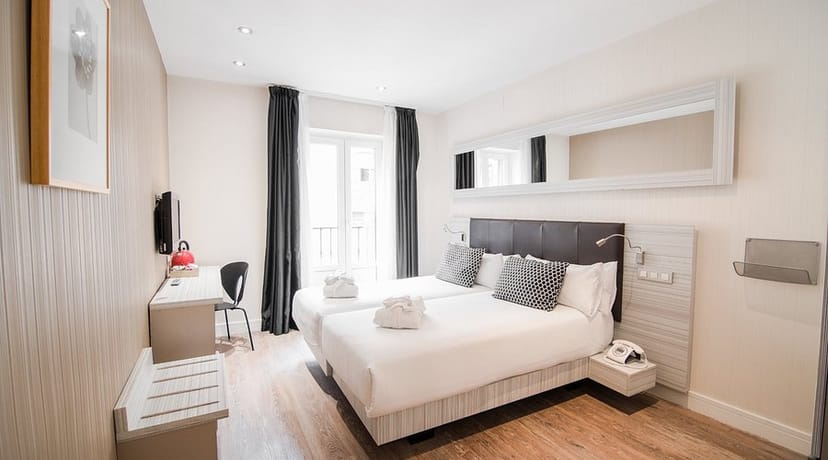 Modern hotel room with twin beds and workspace for corporate business travel.